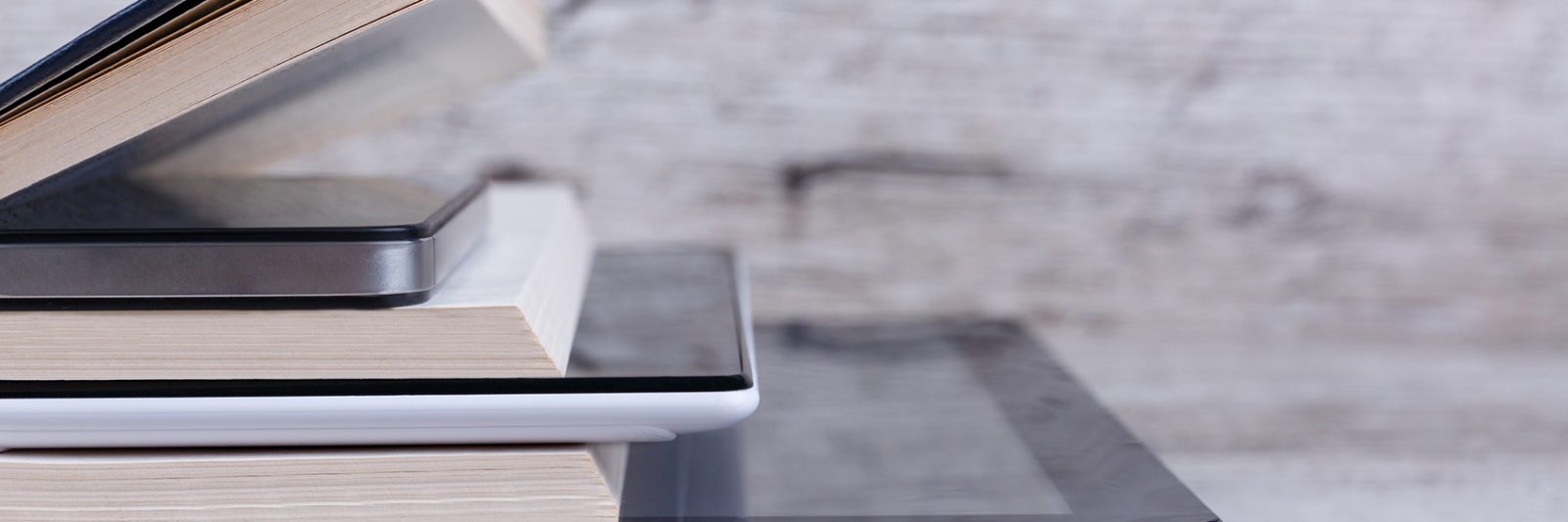 A stack of print books and ereaders formatted for self-publishing.