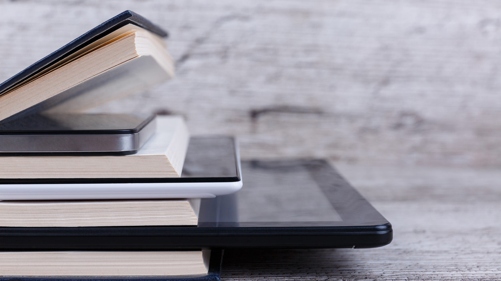 A stack of print books and ereaders formatted for self-publishing.